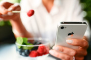 Woman eating fruits dessert with iPhone 4s in hands